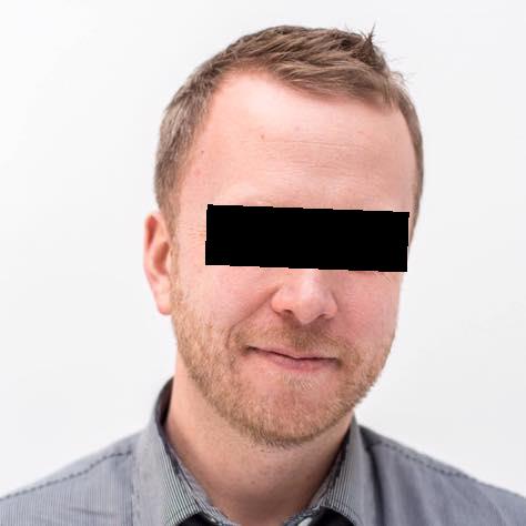 A man with the eye region censored by a black rectangle